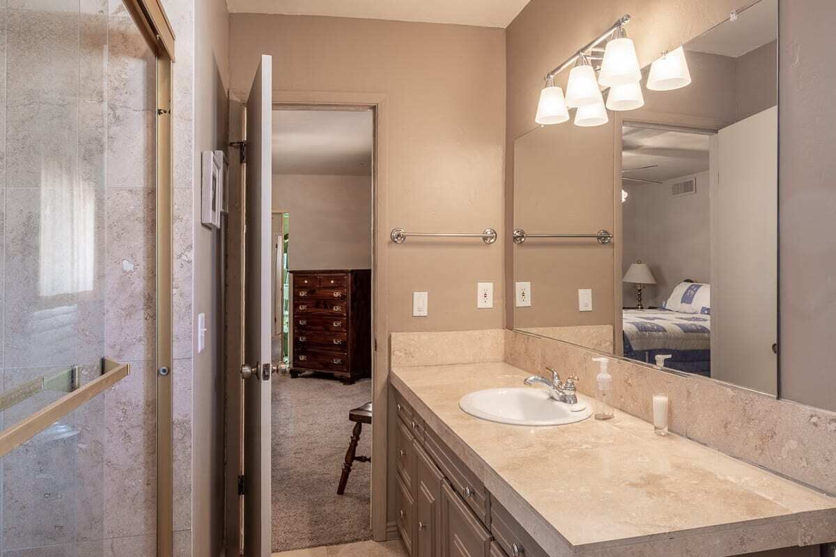 A bathroom with a large mirror, a sink, and a towel rack.