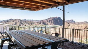 An outdoor patio with a wooden table and chairs, overlooking a mountainous landscape. - Bayview Beauty! Private River access and mountain views! (Parker)
