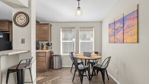 A kitchen with a dining area, wooden cabinets, a clock, and a painting on the wall. - Bayview Beauty! Private River access and mountain views! (Parker)