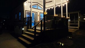 En overdækket udendørs terrasse med trapper op til en dør, omgivet af mure og et gelænder.