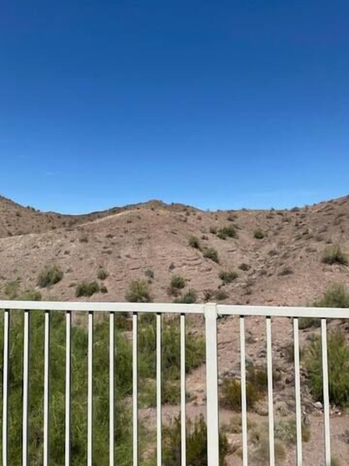 Un paysage désertique avec une végétation clairsemée et un ciel bleu dégagé.