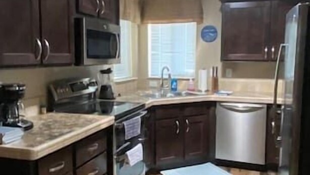 Una cocina con gabinetes de madera oscura, un refrigerador de acero inoxidable, un microondas y una cafetera.