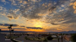 A sunset over a coastal town with visible buildings, palm trees, and a clear sky. - Shoshone One Bedroom with Lake and Pool Views (Lake Havasu City)