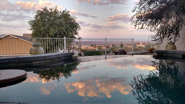 A tranquil outdoor pool area with a clear view of the surrounding landscape, including a large tree and distant mountains. - Shoshone One Bedroom with Lake and Pool Views (Lake Havasu City)