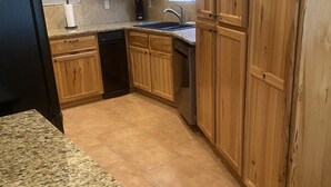 A kitchen with wooden cabinets, a granite countertop, a dishwasher, and a sink. - Shoshone One Bedroom with Lake and Pool Views (Lake Havasu City)