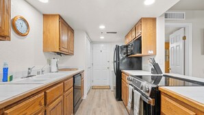 Una cucina con mobili in legno, un frigorifero in acciaio inossidabile, un fornello e un forno a microonde.