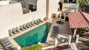 A rooftop pool with lounge chairs, a hot tub, and a patio area with tables and chairs.