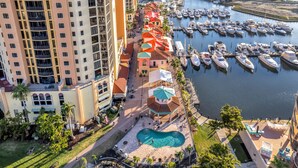 A marina with boats docked, a swimming pool, and a building with balconies. - Condo w/ Views & Resort Amenities in Cape Harbour! (Cape Coral)