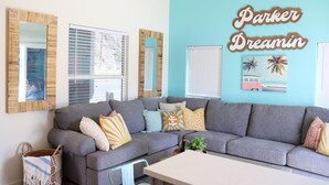 A living room with a grey sofa, multiple cushions, and a wall with a 'Parker Dreamin'' sign.