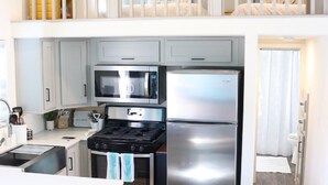 A modern kitchen with a central island, stainless steel appliances, and a dining area with two stools.