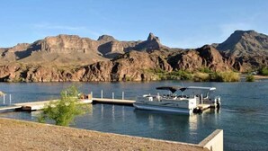 A boat docked at a pier with a mountainous backdrop.