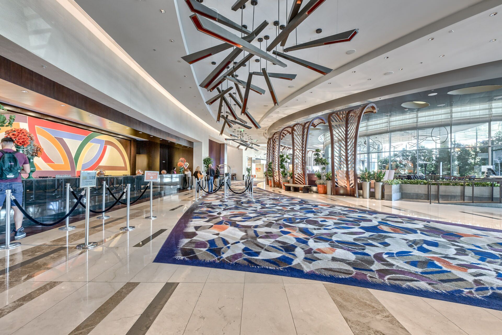 A spacious lobby with a patterned carpet, a reception desk, and a glass wall offering a view of the outdoors.
