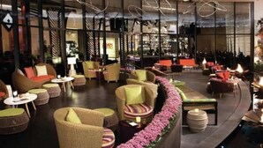 A spacious lounge area with wicker furniture, a central fire feature, and a bar in the background. - Gorgeous Suites Vdara (Las Vegas)