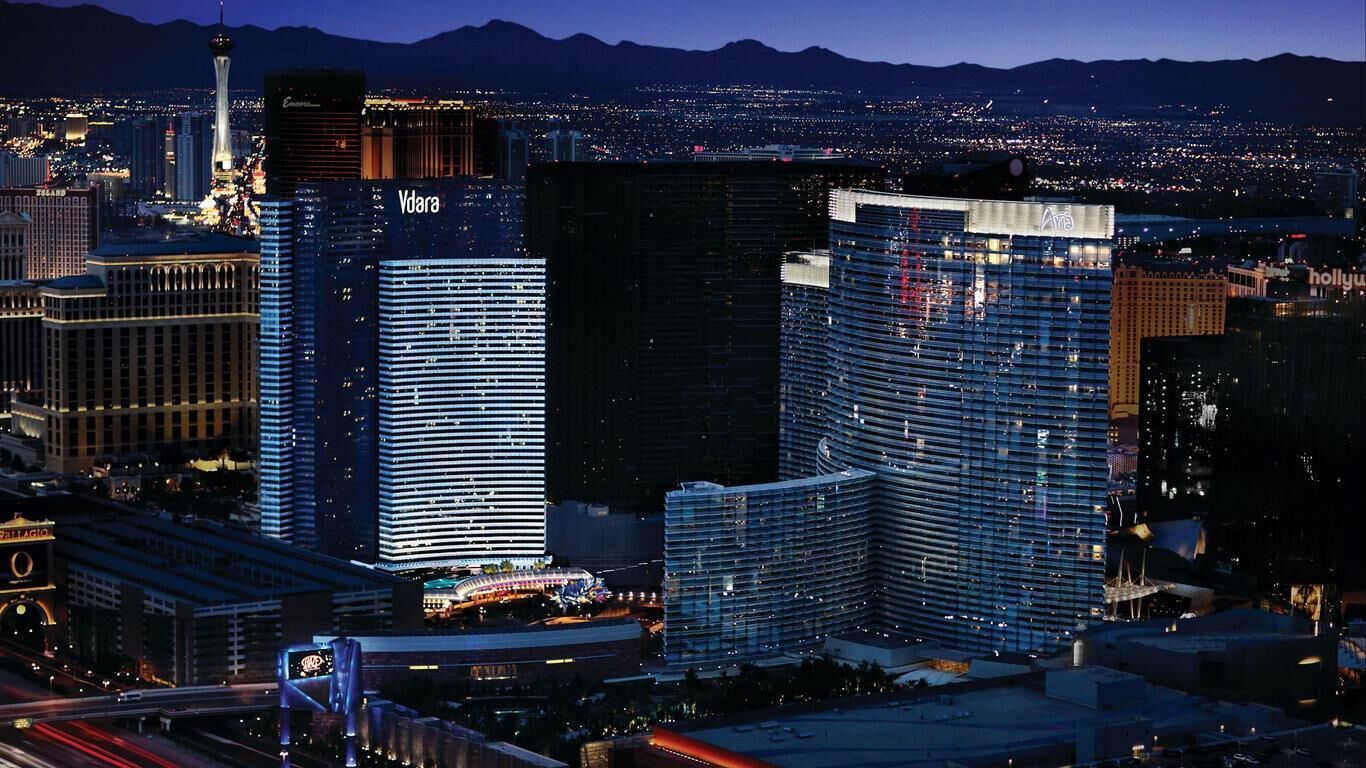 Paesaggio urbano notturno con edifici importanti, tra cui un hotel con insegna illuminata e un casinò.