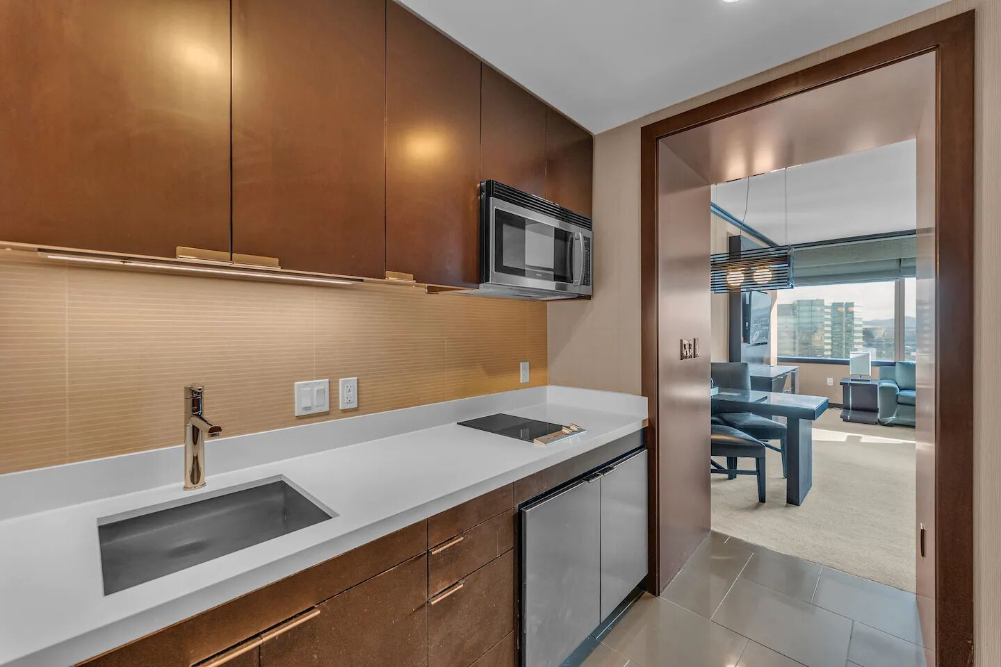 A modern kitchen with stainless steel appliances, a white countertop, and wooden cabinets.