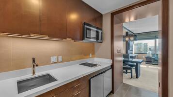 A modern kitchen with stainless steel appliances, a white countertop, and wooden cabinets.
