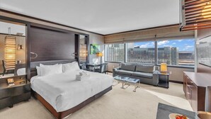 A modern hotel room with a large bed, a sofa, a desk, and a view of the city. - Gorgeous Suites Vdara (Las Vegas)