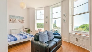 A room with a bed, a leather sofa, a window with a view, and a radiator.