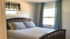 A bedroom with a wooden bed, a window with curtains, and a ceiling light. - Cabin by lake, pet friendly, quiet (Hot Springs)