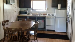 A compact kitchen with wooden cabinets, a microwave, a stove, and a refrigerator. - Cabin by lake, pet friendly, quiet (Hot Springs)
