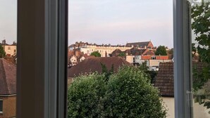 A view of a cityscape through a window, featuring a mix of residential buildings and a prominent historical structure in the background. - Modern Spacious Apartment Families & Corporate (Hove)