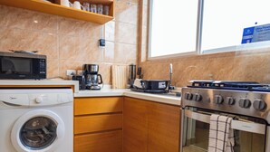 A kitchen with a washing machine, coffee maker, and a stove. - Tranquil Villa in Jolly Harbour with Pool & Modern Amenities (St. Mary's)