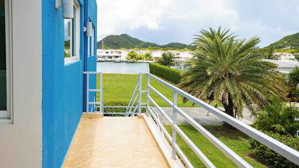 A balcony with a view of a marina and hills. - Tranquil Villa in Jolly Harbour with Pool & Modern Amenities (St. Mary's)