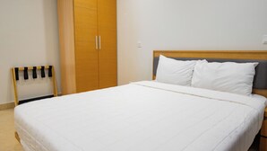 A bedroom with a large bed, a wardrobe, and a small chair. - Tranquil Villa in Jolly Harbour with Pool & Modern Amenities (St. Mary's)