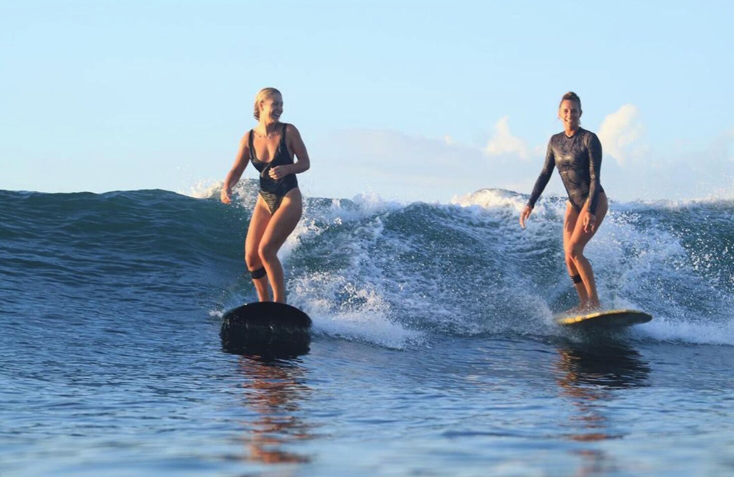 Zwei Personen surfen auf einer Welle.