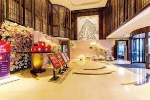 A hotel lobby with a central reception area, a large wall mural, and a circular floor design.