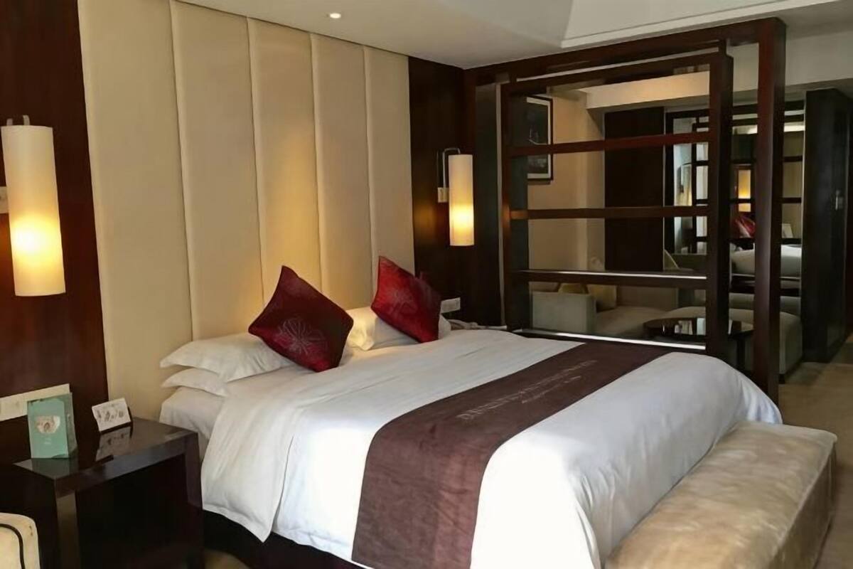 Een hotelkamer met een groot bed, nachtkastjes, een bureau en uitzicht op de gang.