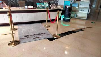 Un área de recepción con piso de mármol, mostrador de recepción y una barrera de cuerda roja.