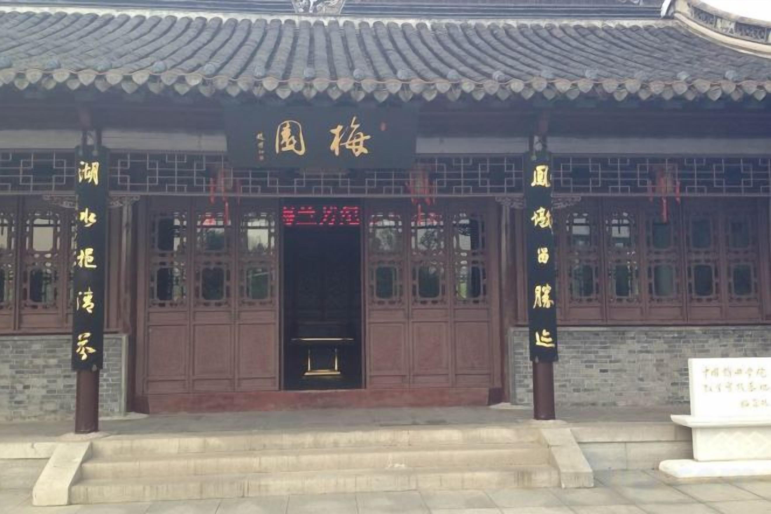 A traditional building with a tiled roof, a wooden door with a sign above it, and a stone base.