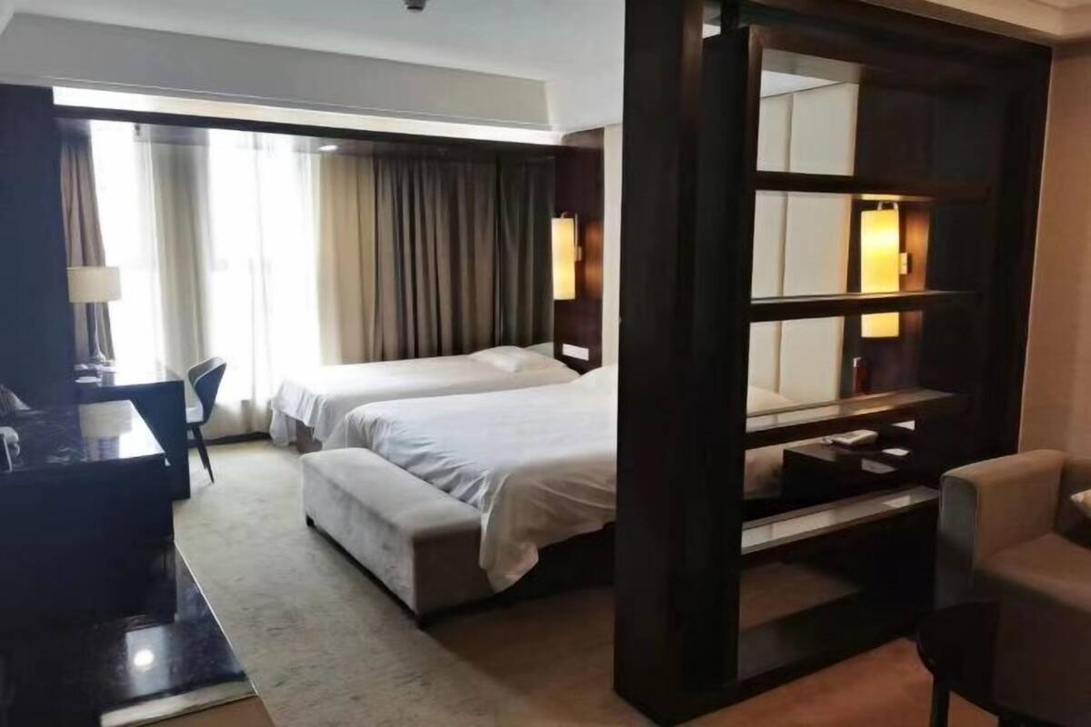 Een hotelkamer met twee bedden, een bureau, een stoel en een grote spiegel.