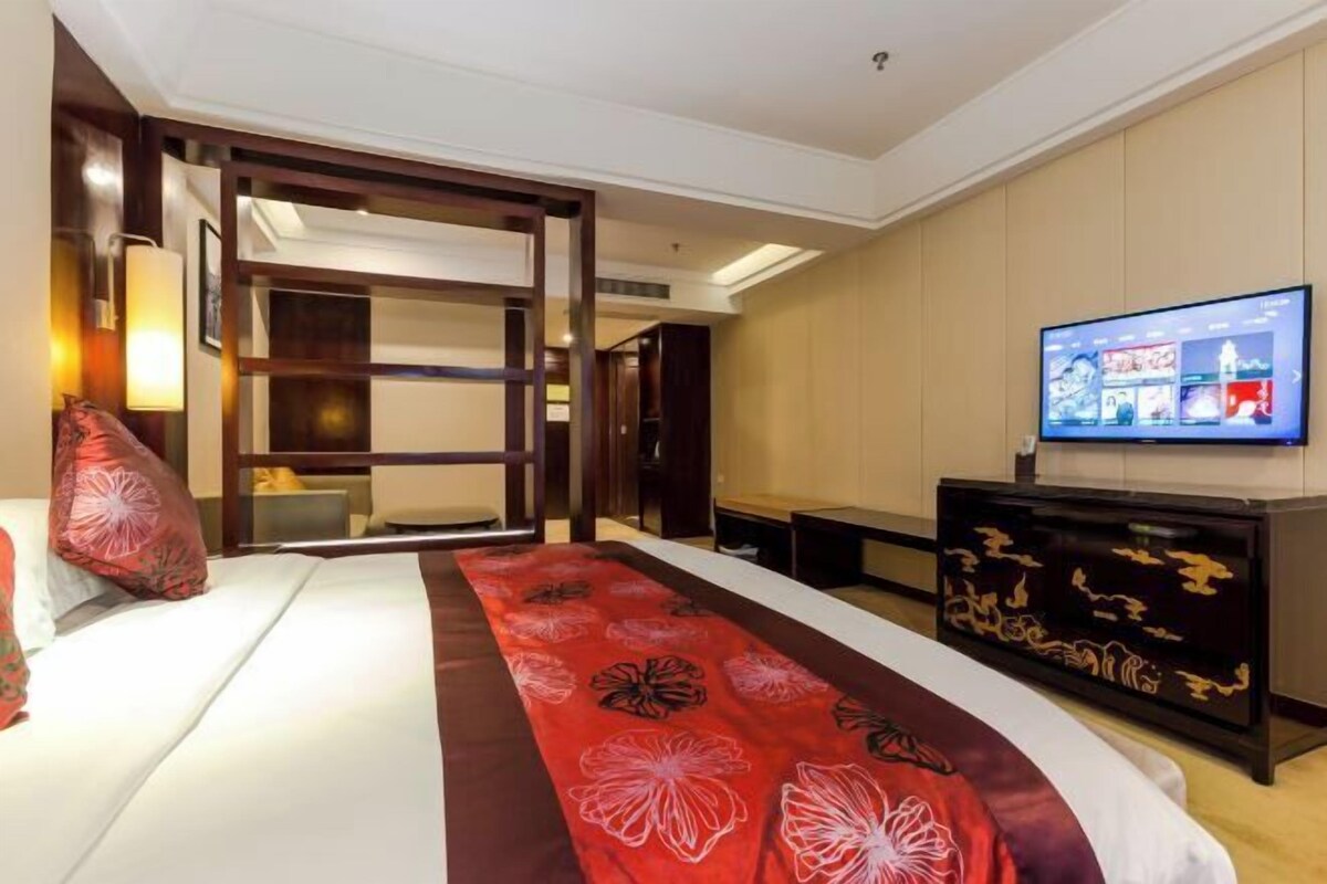 A hotel room with a bed, a television, a desk, and a decorative red carpet.
