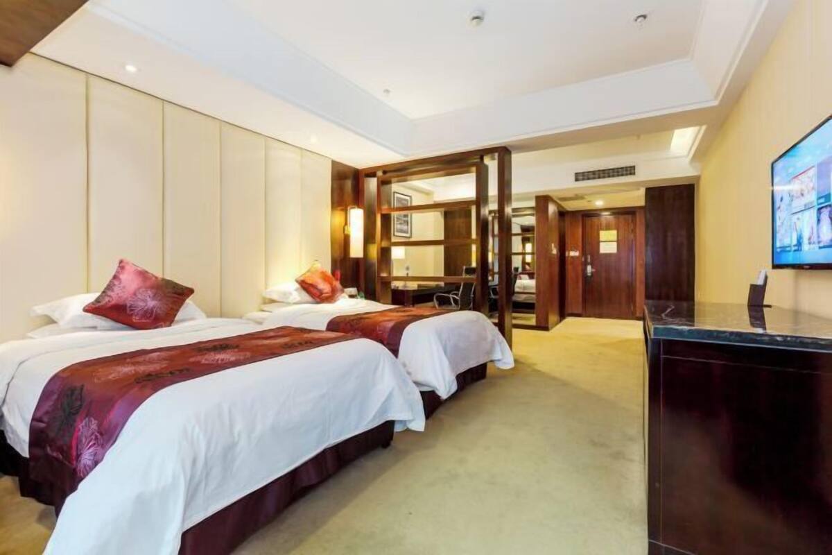 Een hotelkamer met twee bedden, een bureau en een televisie.