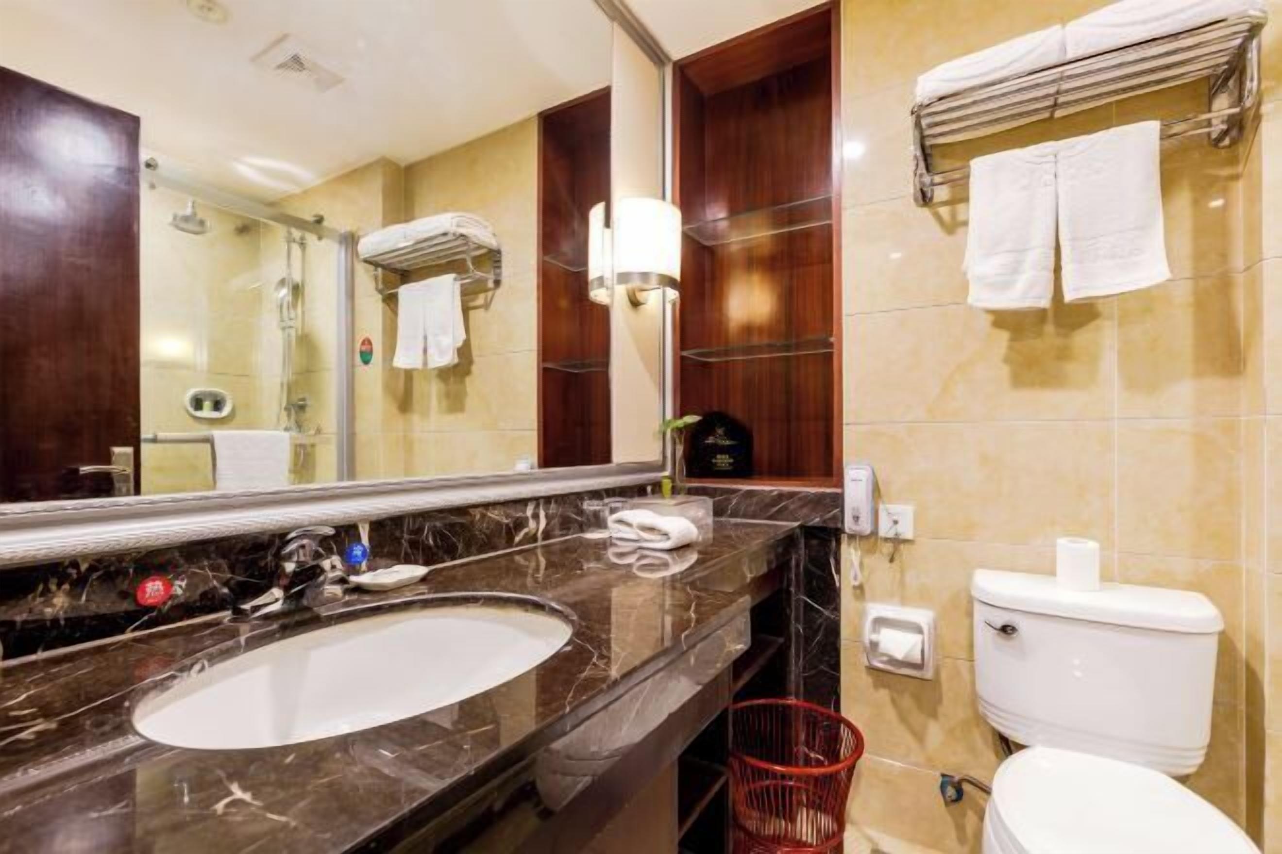 A bathroom with a marble sink, a mirror, a toilet, and a towel rack.