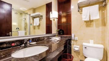 A bathroom with a marble sink, a mirror, a toilet, and a towel rack.
