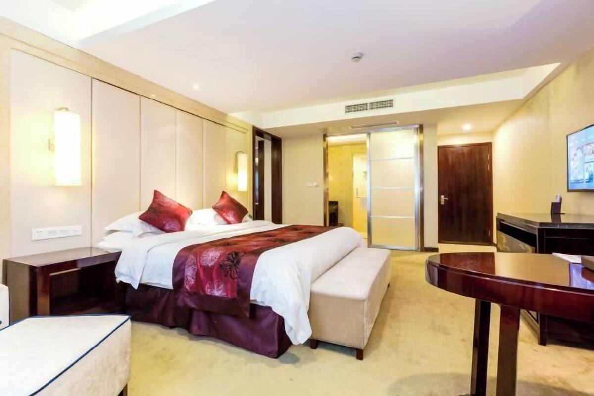Een hotelkamer met een bed, nachtkastjes, een bureau en een televisie.