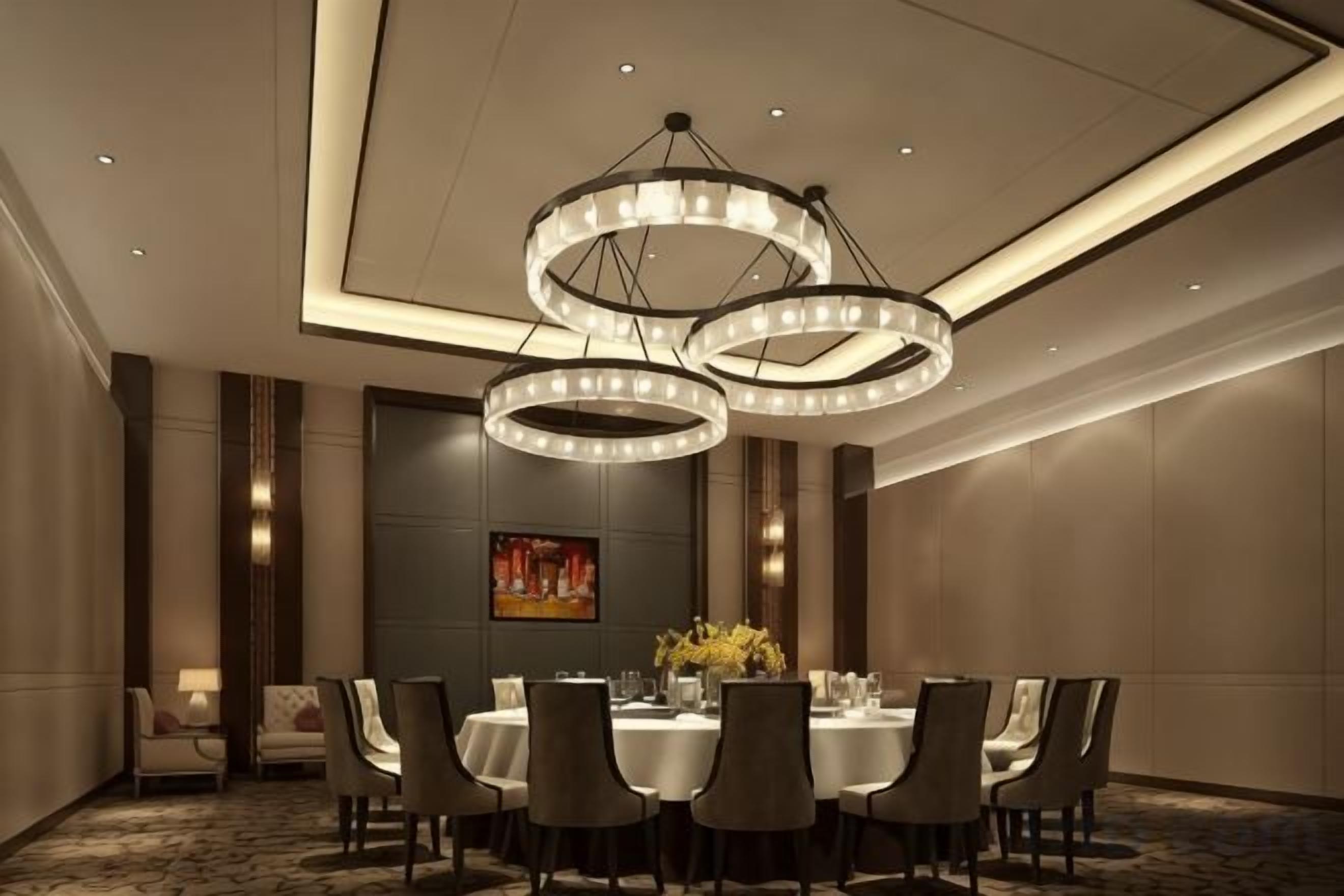 A conference room with a round table, chairs, and a chandelier.