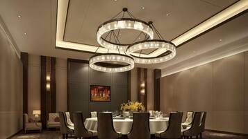A conference room with a round table, chairs, and a chandelier.