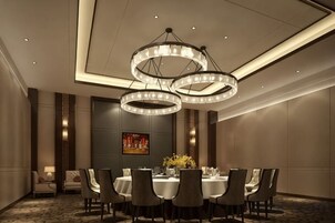 Un salón de conferencias con una mesa redonda, sillas y un candelabro.