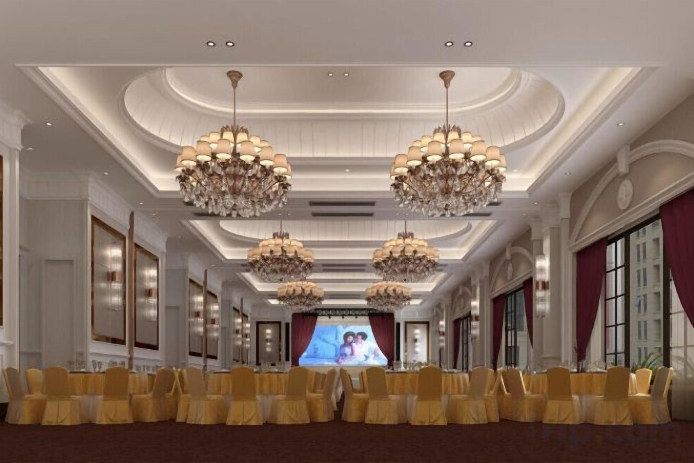 A formal event space with rows of chairs, chandeliers, and a large screen.
