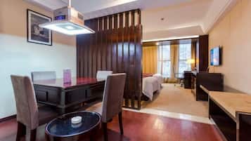 A hotel room with a dining table, chairs, a bed, a TV, and a large window.