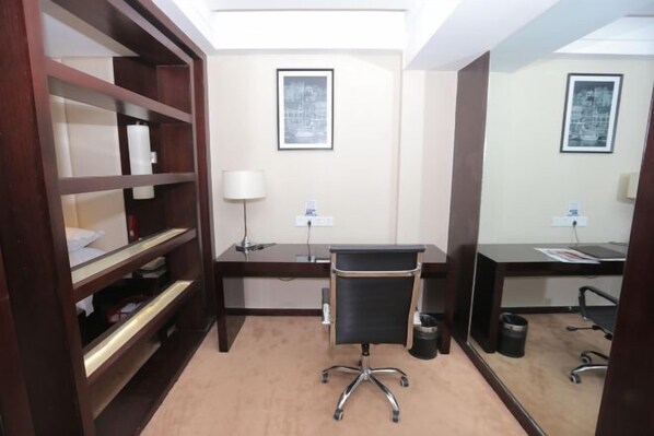 A hotel room with a desk, chair, bookshelf, two framed pictures on the wall, and a carpeted floor. - Century Yuan International hotel(Jiangyan,Taizhou) (Taizhou)