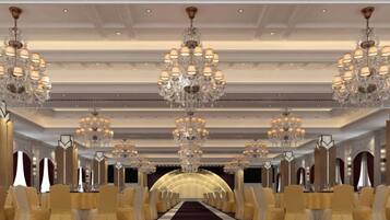 A long, narrow room with rows of chairs and a central aisle, large chandeliers, and a carpeted floor.