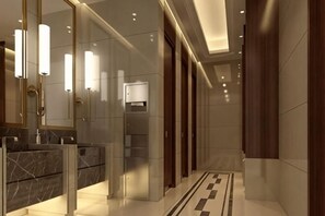 Un baño moderno con lavamanos de mármol, un espejo grande y un suelo estampado.