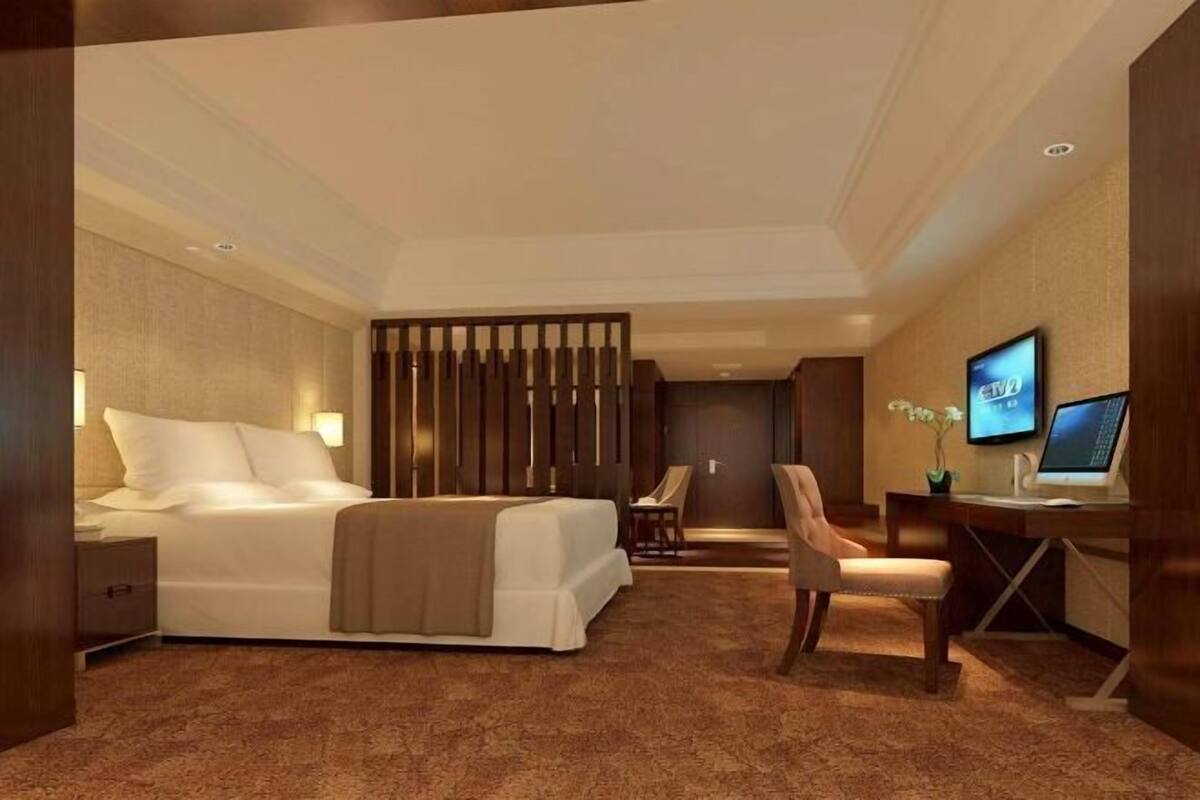 Een hotelkamer met een bed, bureau, stoelen en een televisie.