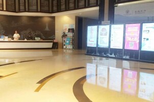 A reception area with a counter, digital information boards, and a polished floor.