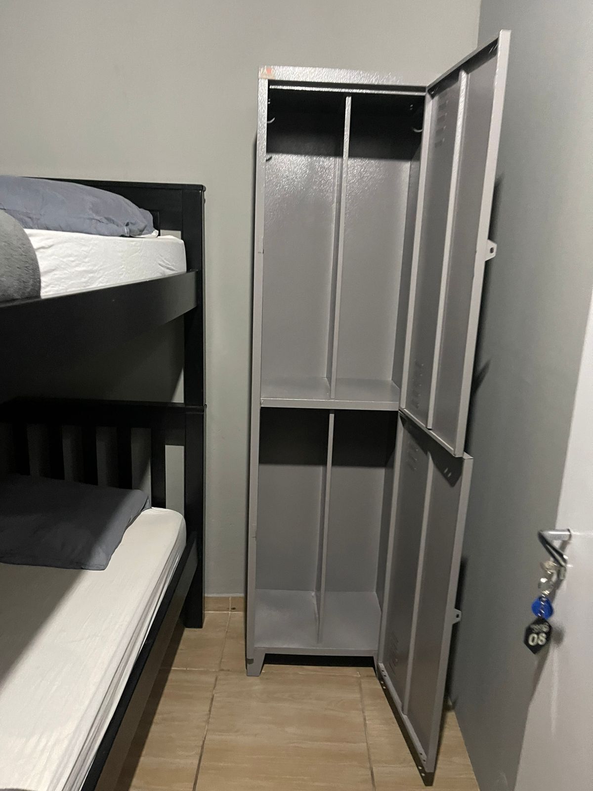 A bunk bed with a grey headboard and a small wardrobe with a sliding door.